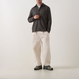 Model wearing Calvin Klein Garment Wash Twill Shirt in Beluga, dark grey twill with point collar and chest pockets, styled with cream wide-leg