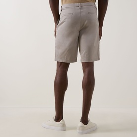 Model wearing light grey chino shorts, rear view, styled with white trainers