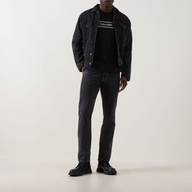 Model wearing Calvin Klein 20S SPW Graphic Logo T-Shirt in black, styled with dark denim jacket, grey jeans, and black shoes.