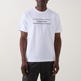 Model wearing Calvin Klein 20S SPW Graphic Logo T-Shirt in Bright White, crew neck, with contrast logo print across chest, paired with black trousers.