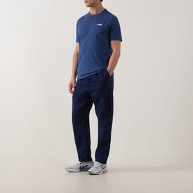 Model wearing Calvin Klein 30S Graphic Logo T-Shirt in Dark Denim, crew neck, short sleeves, styled with navy trousers and grey trainers.