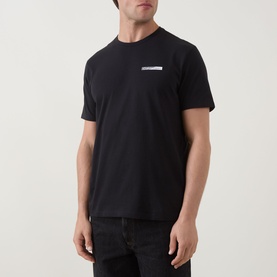Model wearing Calvin Klein 30S Graphic Logo T-Shirt in black, crew neck with chest logo detail, paired with dark jeans.