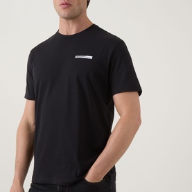 Model wearing Calvin Klein 30S Graphic Logo T-Shirt in black, crew neck with small chest logo detail, paired with dark jeans
