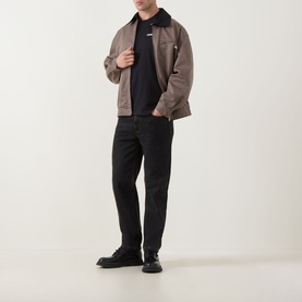 Model wearing Calvin Klein 30S Graphic Logo T-Shirt in Black, styled with a taupe harrington jacket and black straight-leg trousers.