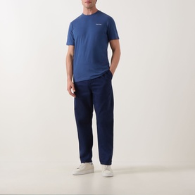 Model wearing Calvin Klein Micro Logo T-Shirt in Dark Denim, crew neck, short sleeves, styled with navy trousers and white trainers.