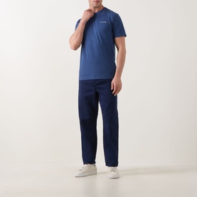 Model wearing Calvin Klein Micro Logo T-Shirt in Dark Denim, crew neck, short sleeves, styled with navy trousers and white trainers.