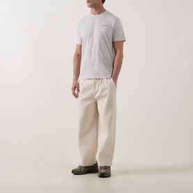Model wearing Calvin Klein Micro Logo T-Shirt in Moonstruck, crew neck, short sleeves, styled with cream wide-leg trousers and khaki trainers.