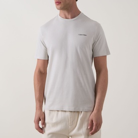 Model wearing Calvin Klein Micro Logo T-Shirt in Moonstruck, crew neck, short sleeves with chest logo, styled with cream trousers.