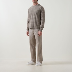 Model wearing Calvin Klein Tonal Slub Knitted Sweater in Roast Cashew, crew neck, long sleeves, styled with taupe trousers and white trainers.