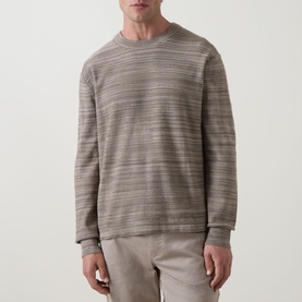 Model wearing Calvin Klein Tonal Slub Knitted Sweater in Roast Cashew, crew neck, long sleeves, tonal slub stripe detail, styled with beige trousers.