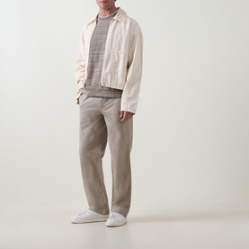 Model wearing Calvin Klein Tonal Slub Knitted Sweater in Roast Cashew HMT, styled with cream jacket and taupe trousers.