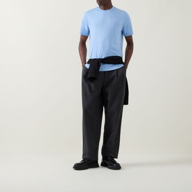 Model wearing Calvin Klein Monogram Logo T-Shirt in Placid Blue, crew neck, short sleeves, styled with black wide-leg trousers and loafers.