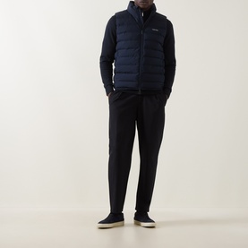 Model wearing Calvin Klein Lightweight Quilted Gilet in Dark Sapphire, styled with navy trousers and grey trainers.