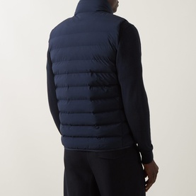 Model wearing Calvin Klein Lightweight Quilted Gilet in Dark Sapphire, back view, styled over a navy knit jumper.