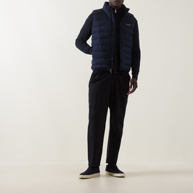 Model wearing Calvin Klein Lightweight Quilted Gilet in Dark Sapphire, styled with a navy knit sweater and black trousers.
