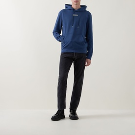 Model wearing Calvin Klein Dark Denim hoodie with kangaroo pocket, styled with black slim-fit jeans and black leather shoes.