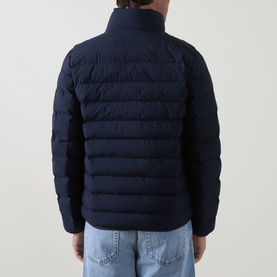 Model wearing Calvin Klein Logo Padded Jacket in Dark Sapphire, quilted back panel, funnel neck, styled with light blue jeans.