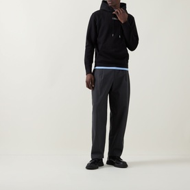 Model wearing Calvin Klein 350 Terry Stack Logo Hoodie in black with dark tailored trousers and black chunky loafers.