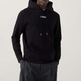 Model wearing Calvin Klein 350 Terry Stack Logo Hoodie in black with kangaroo pocket and chest logo detail, styled with grey trousers