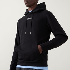 Model wearing Calvin Klein 350 Terry Stack Logo Hoodie in black with kangaroo pocket and chest logo, styled with a light blue shirt.