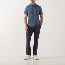 Model wearing Calvin Klein Badge Logo Polo Shirt in Dark Slate, short sleeves, chest badge detail, styled with navy chinos and white trainers.