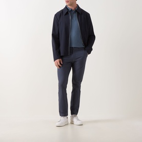 Model wearing Calvin Klein Badge Logo Polo Shirt in Dark Slate, styled with a navy zip jacket, navy trousers and white trainers.
