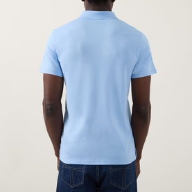 Model wearing Calvin Klein Badge Logo Polo Shirt in Placid Blue, rear view, styled with dark blue jeans