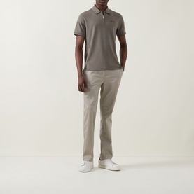 Model wearing Calvin Klein Supima Slim Zip Polo Shirt in Bungee Cord, half zip placket, ribbed cuffs, styled with beige chinos and white trainers.