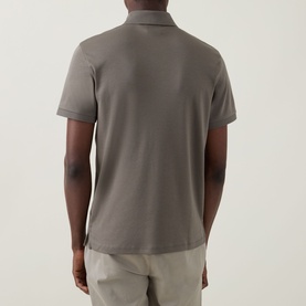 Model wearing Calvin Klein Supima Slim Zip Polo Shirt in Bungee Cord, rear view showing straight hem and short sleeves, paired with light trousers
