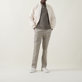 Model wearing Calvin Klein Supima Slim Zip Polo in Bungee Cord, styled with cream quilted bomber jacket and taupe chinos.