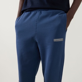 Model wearing Calvin Klein 350 Logo Sweatpants in Dark Denim, elasticated waistband, logo badge detail, terry cotton fabric