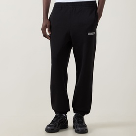Model wearing Calvin Klein 350 Logo Sweatpants in black, cuffed terry cotton joggers with logo badge, styled with chunky trainers