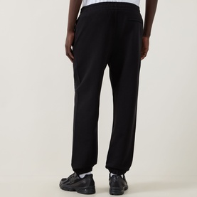 Model wearing Calvin Klein 350 Logo Sweatpants in black, cuffed terry cotton style, shown from behind with black chunky trainers.