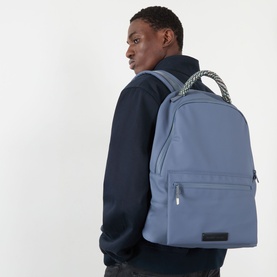 Model carrying Samsoe & Samsoe Satom Logo Backpack in Folkstone Gray, featuring woven top handle, front zip pocket and adjustable straps