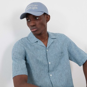 Model with Samsoe & Samsoe Summer Nostalgia Baseball Cap in Folkstone Nostalgia, curved brim with contrast embroidery. Styled with striped shirt.