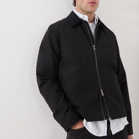 Model wearing Samsoe & Samsoe Robin Zip-Up Jacket in black, styled over a white shirt, showing two-way zip and chest pocket detail.