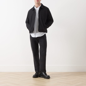 Model wearing Samsoe & Samsoe Robin Zip-Up Jacket in black, styled with a white shirt, dark trousers and black leather shoes.