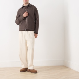 Model wearing Samsoe & Samsoe Paulo Zip Overshirt in Turkish Coffee with cream trousers and brown suede loafers