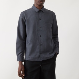 Model wearing Samsoe & Samsoe Casual Shirt in Salute Mel., featuring button-front, chest pocket and long sleeves, styled with black trousers.