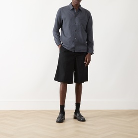 Model wearing Samsoe & Samsoe Salute Mel. casual shirt with black shorts and Chelsea boots.