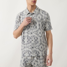 Model wearing Samsoe & Samsoe Casual Shirt in Salute Symmetry, short-sleeve camp collar with all-over abstract print, styled with matching trousers.