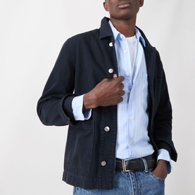 Model wearing Samsoe & Samsoe Ryan Stripe Shirt in Windsurfer St., styled under a dark navy chore jacket with a black belt.