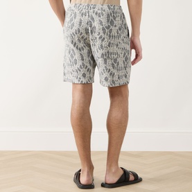 Model wearing Samsoe & Samsoe Salute Symmetry shorts, rear view, with black slip-on sandals. Abstract grey print, elasticated waist.
