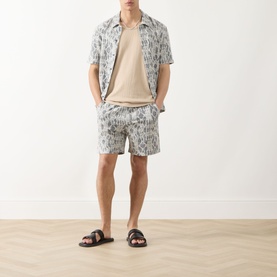 Model wearing Samsoe & Samsoe Salute Symmetry shorts with matching printed shirt, beige tee, and black leather sandals