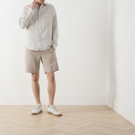 Model wearing Samsoe & Samsoe Smith Lightweight Shorts in Aluminium, styled with a grey striped shirt and white trainers.