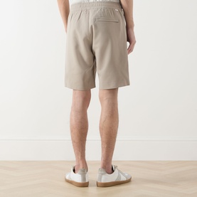 Model wearing Samsoe & Samsoe Smith Lightweight Shorts in Aluminium, rear view, elasticated waistband, zipped back pocket, with white trainers.