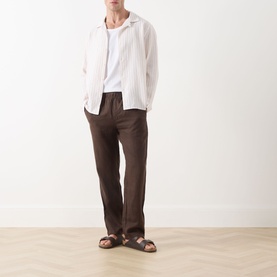 Model wearing Samsoe & Samsoe Jabari Casual Trousers in Turkish Coffee linen, styled with a white shirt and brown sandals.