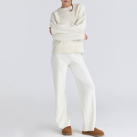 Model wearing House of CB ivory knit oversized sweater and wide-leg trousers set, styled with tan boots