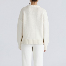 Model wearing House of CB ivory knit sweater, rear view, relaxed fit with ribbed hem, styled with white trousers