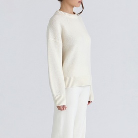 Model wearing House of CB ivory knit crew-neck sweater with ribbed cuffs and hem, styled with matching wide-leg trousers